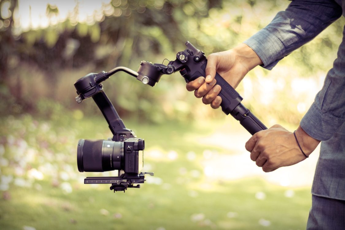 image showing two hands holding a camera attached to a gimbal.