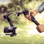 image showing two hands holding a camera attached to a gimbal.